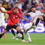 لقطة من مباراة كرة قدم بين منتخبي مصر وإيران في كأس العالم، تظهر لاعبين يتنافسون على الكرة.