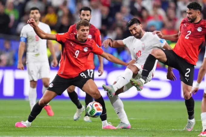 لقطة من مباراة كرة قدم بين منتخبي مصر وإيران في كأس العالم، تظهر لاعبين يتنافسون على الكرة.