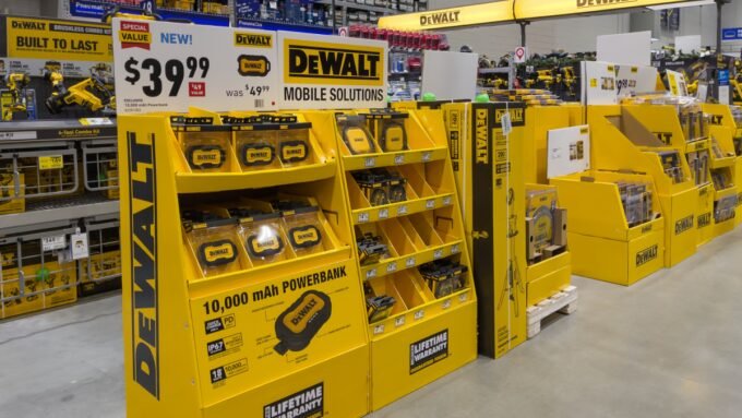 A collection of DeWalt yellow and black cordless power tools, including a drill, impact driver, and saw, displayed against a workshop background.