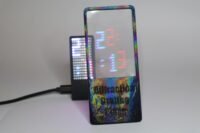 A close-up view of Moritz Von Sivers' diffraction grating clock, showing blue hours and red minutes separated by light refraction on an LED display.