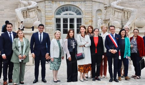 Vue du Château de Fontainebleau, avec des drapeaux marocains et français flottant, et des visiteurs explorant les expositions artistiques marocaines.