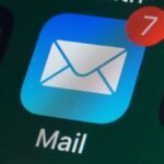 A person's hand holding an iPhone with a blurred background, symbolizing digital privacy and email protection.