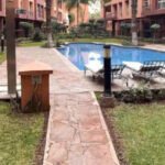 Vue aérienne d'une villa de luxe avec piscine et jardins luxuriants à Marrakech, sous un ciel bleu, symbolisant l'essor du marché immobilier premium de la ville.
