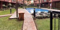Vue aérienne d'une villa de luxe avec piscine et jardins luxuriants à Marrakech, sous un ciel bleu, symbolisant l'essor du marché immobilier premium de la ville.