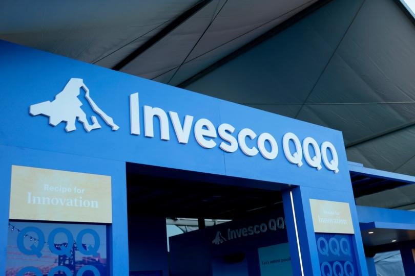 Invesco logo alongside digital assets and blockchain imagery, representing their new tokenized stablecoin reserve fund.