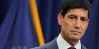 Kevin Warsh, the new Federal Reserve Chair, speaking at a press conference with a serious expression, symbolizing his firm stance on monetary policy.