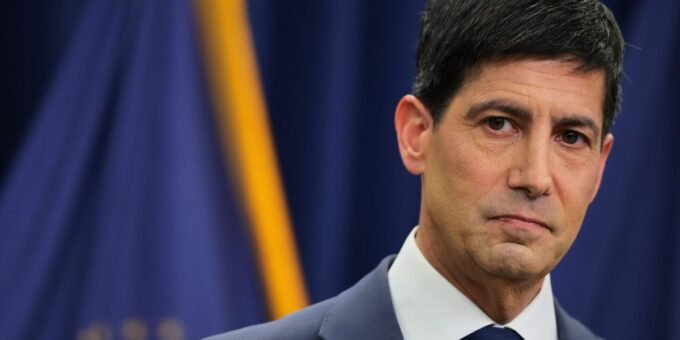 Kevin Warsh, the new Federal Reserve Chair, speaking at a press conference with a serious expression, symbolizing his firm stance on monetary policy.