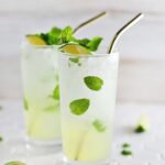 A refreshing mint Mojito cocktail in a tall glass with lime slices and fresh mint sprigs