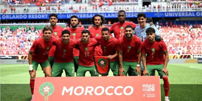 L'équipe nationale marocaine, les Lions de l'Atlas, en pleine discussion avec leur staff technique sur un terrain de football, symbolisant la préparation aux nouvelles règles de la FIFA pour la Coupe du Monde 2026.