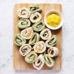 A vibrant platter of colorful pinwheel sandwiches, neatly sliced and arranged, ready to be served.