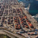 Vue aérienne du port de Tanger Med, avec des porte-conteneurs amarrés et des grues en activité, symbolisant l'efficacité et la modernité portuaire.