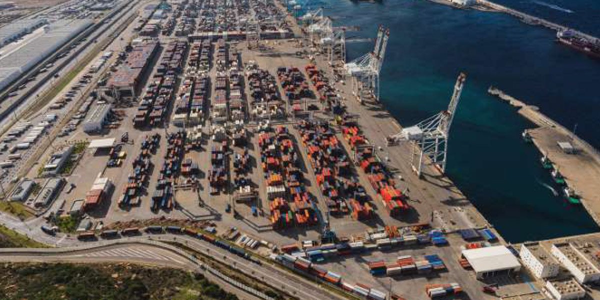 Vue aérienne du port de Tanger Med, avec des porte-conteneurs amarrés et des grues en activité, symbolisant l'efficacité et la modernité portuaire.