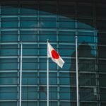 Ripple RLUSD stablecoin logo against a backdrop of Japanese financial buildings, symbolizing regulatory approval and market entry.