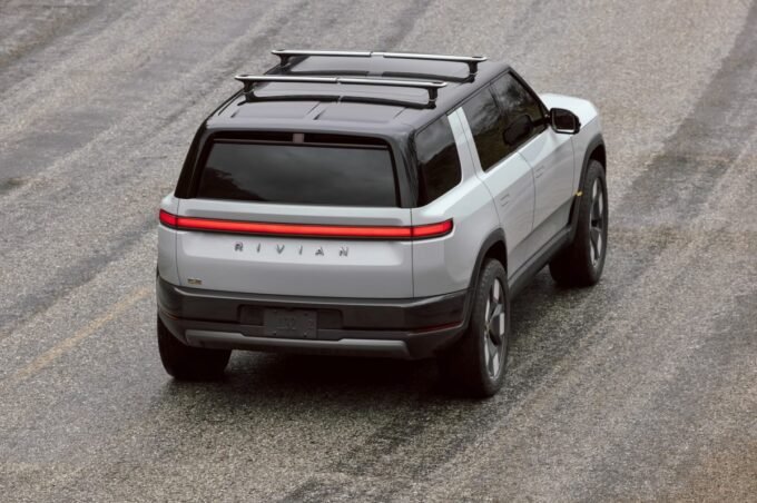 Rivian R2 SUV on a delivery truck, symbolizing the company's dual challenges of market launch and workforce restructuring.