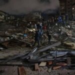 Vue aérienne de bâtiments endommagés après un séisme au Venezuela, avec des débris éparpillés et des équipes de secours en action.
