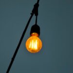A smart light bulb glowing in a modern home setting, possibly with a smartphone controlling it.
