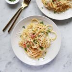 A beautifully plated dish of spaghetti carbonara, garnished with crispy pancetta and fresh parsley.