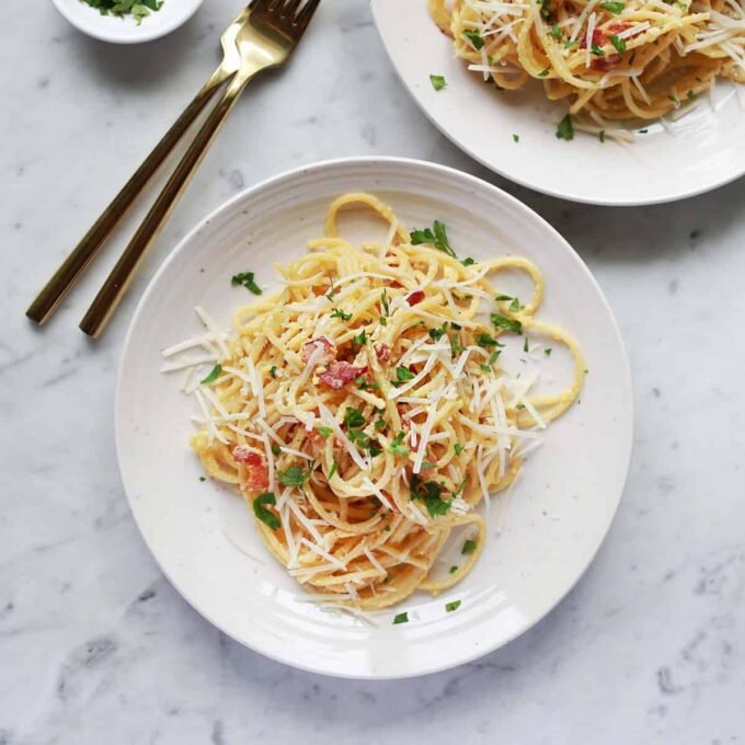 A beautifully plated dish of spaghetti carbonara, garnished with crispy pancetta and fresh parsley.