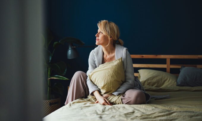 Woman meditating or practicing yoga, representing balance and wellness, with subtle Ayurvedic symbols in the background.