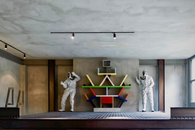 A modern Brutalist home interior in Milan featuring exposed concrete, a sculptural staircase, and contemporary art.