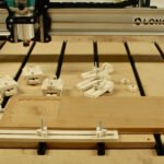 Elevate Your CNC Projects: Simple, Universal DIY Workholding Clamps 8 Two types of DIY CNC workholding clamps made from plywood, securing a workpiece on a CNC router bed.