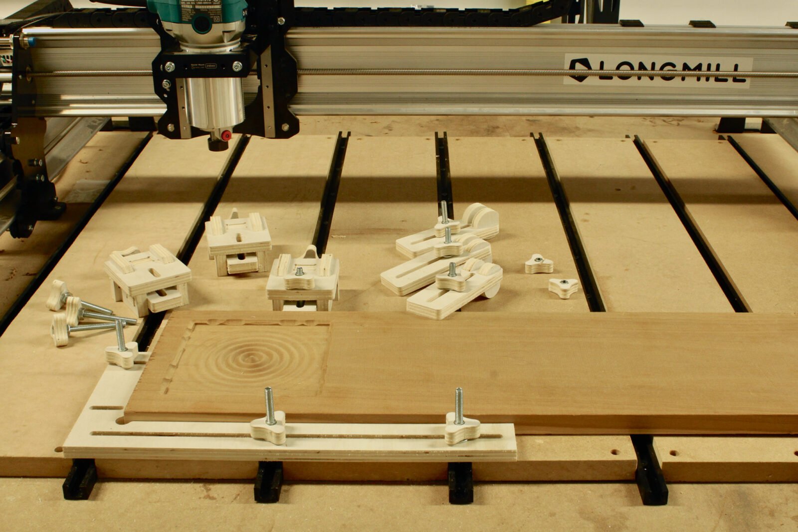 Elevate Your CNC Projects: Simple, Universal DIY Workholding Clamps 3 Two types of DIY CNC workholding clamps made from plywood, securing a workpiece on a CNC router bed.