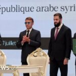 صورة تظهر الرئيس الفرنسي إيمانويل ماكرون والرئيس السوري أحمد الشرع خلال مؤتمر صحفي في دمشق، مع خلفية لعلمي البلدين.