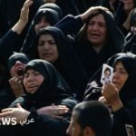 تابوت الإمام روح الله الخميني محاطاً بحشود غفيرة في ساحة مصلى طهران خلال مراسم تشييعه عام 1989.