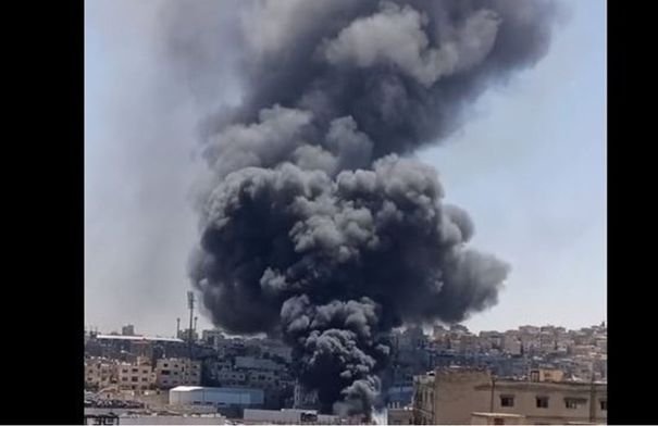 صورة تظهر أعمدة دخان أسود كثيفة وألسنة لهب تتصاعد من مبنى سكني وتجاري في منطقة القويسمة بعمان، مع تواجد لفرق الدفاع المدني.