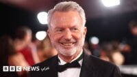 صورة للممثل سام نيل في حفل جوائز، يبتسم وهو ينظر إلى الجمهور.