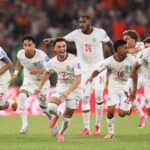 صورة تجمع لاعبي المنتخب المغربي يحتفلون بفوزهم في كأس العالم، مع شعار كأس العالم 2026 في الخلفية.