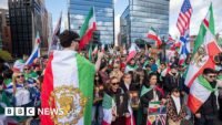 صورة لحشود تشارك في مراسم تشييع المرشد الأعلى الإيراني الراحل علي خامنئي، مع إشارة إلى التوترات الإقليمية والمفاوضات الدبلوماسية.