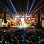 صورة لجمهور غفير يتفاعل مع الفنانين على منصة مهرجان تيميتار بأكادير ليلاً