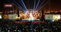 صورة لجمهور غفير يتفاعل مع الفنانين على منصة مهرجان تيميتار بأكادير ليلاً
