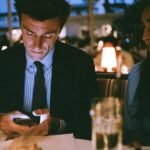An entrepreneur looking stressed while on a date, with business thoughts on their mind, symbolizing the struggle between startup life and personal relationships.