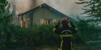 Vue aérienne d'un vaste incendie de forêt en Gironde, avec des flammes intenses et d'épais panaches de fumée s'élevant au-dessus des pins, des véhicules de pompiers au sol et des habitants évacuant.