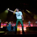 Une foule immense et enthousiaste à Anfa Park lors de Jazzablanca 2026, avec la scène principale illuminée et des écrans géants diffusant le match Maroc-France en arrière-plan, symbolisant la fusion unique de la musique et du sport.
