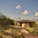 Kitirua Plains Lodge exterior showing curved earth-formed walls blending into the Kenyan landscape with Mount Kilimanjaro in the background.