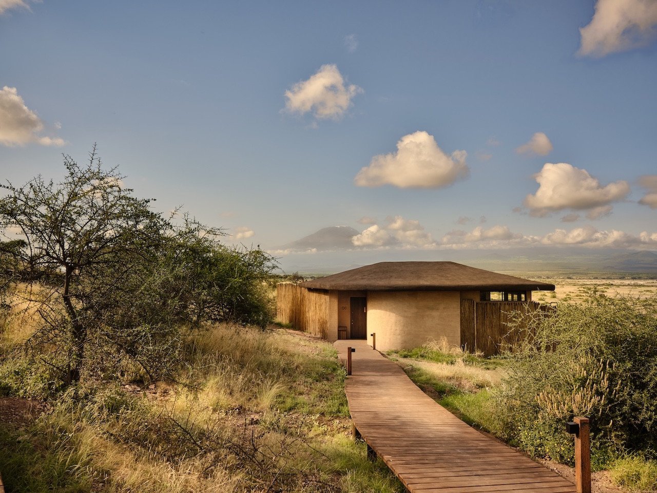 Kitirua Plains Lodge exterior showing curved earth-formed walls blending into the Kenyan landscape with Mount Kilimanjaro in the background.