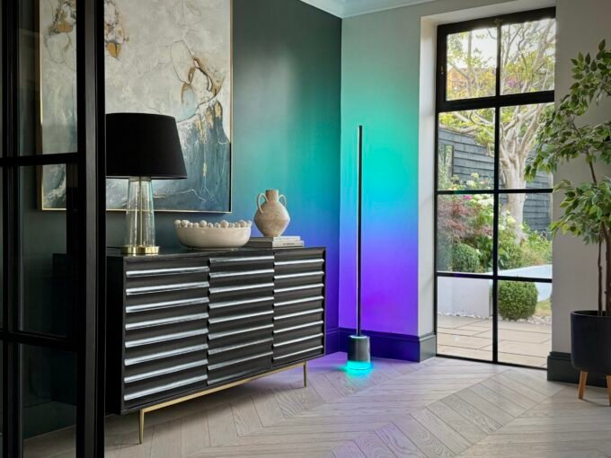 A stylish living room with warm wood tones, a mid-century armchair, and a Govee Floor Lamp 3 casting a soft glow, illustrating layered lighting.