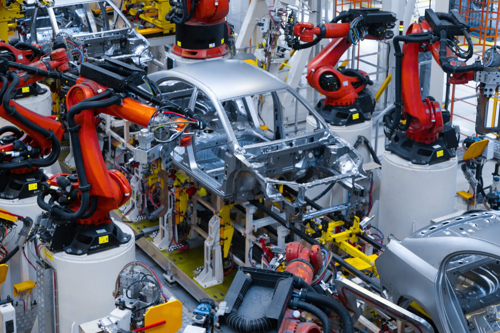 Vue aérienne d'une usine automobile moderne au Maroc, avec des voitures neuves alignées et des camions de transport, symbolisant le succès de l'exportation.