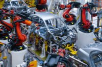 Vue aérienne d'une usine automobile moderne au Maroc, avec des voitures neuves alignées et des camions de transport, symbolisant le succès de l'exportation.
