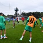 L'équipe nationale marocaine de football, les Lions de l'Atlas, en pleine séance d'entraînement à Boston, avec le sélectionneur Mohamed Ouahbi supervisant les joueurs sur le terrain et un groupe en salle pour la récupération, en préparation pour les quarts de finale de la Coupe du Monde de la FIFA 2026.