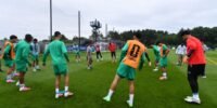 L'équipe nationale marocaine de football, les Lions de l'Atlas, en pleine séance d'entraînement à Boston, avec le sélectionneur Mohamed Ouahbi supervisant les joueurs sur le terrain et un groupe en salle pour la récupération, en préparation pour les quarts de finale de la Coupe du Monde de la FIFA 2026.