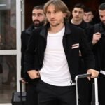 Luka Modric souriant, portant le maillot de l'AC Milan, célébrant un but ou une victoire.