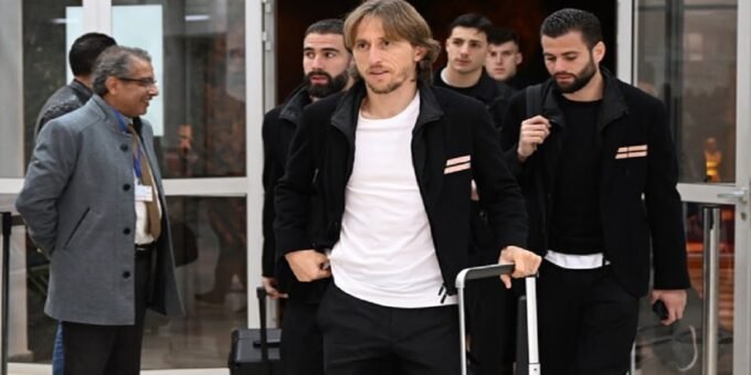 Luka Modric souriant, portant le maillot de l'AC Milan, célébrant un but ou une victoire.