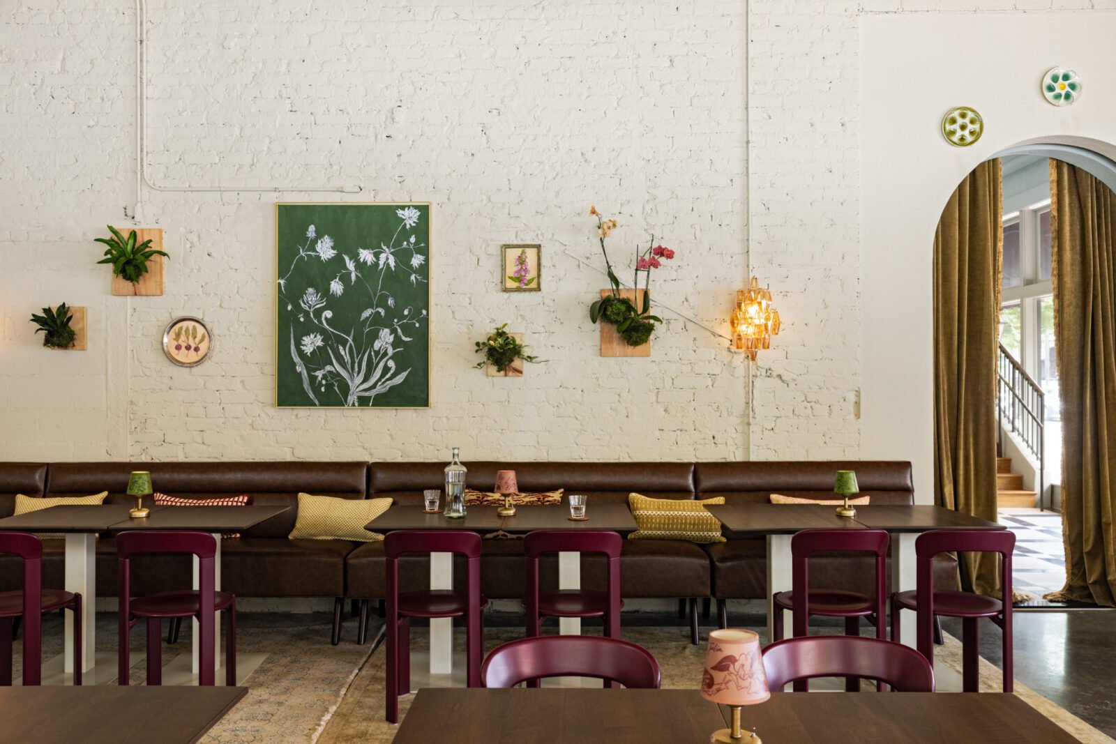 Interior view of Charles & Julia cocktail lounge, featuring oxblood velvet drapery, vintage European furnishings, and a Calacatta Viola marble bar.