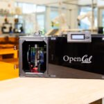 An OpenCAL layerless 3D printer in operation, showing an object forming rapidly within a resin vial.