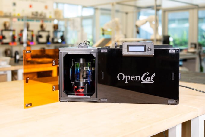 An OpenCAL layerless 3D printer in operation, showing an object forming rapidly within a resin vial.