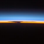 Astronauts aboard the ISS capture the Earth's ozone layer at sunset over Papua, New Guinea, with a thunderhead over Australia.
